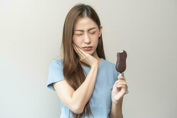 face-expression-suffering-from-sensitive-teeth-and-cold-asian-young-woman-girl-hand-touching-her-cheek-feeling-hurt-pain-eating-ice-cream-lolly-toothache-molar-tooth-at-home-dental-problem-photo